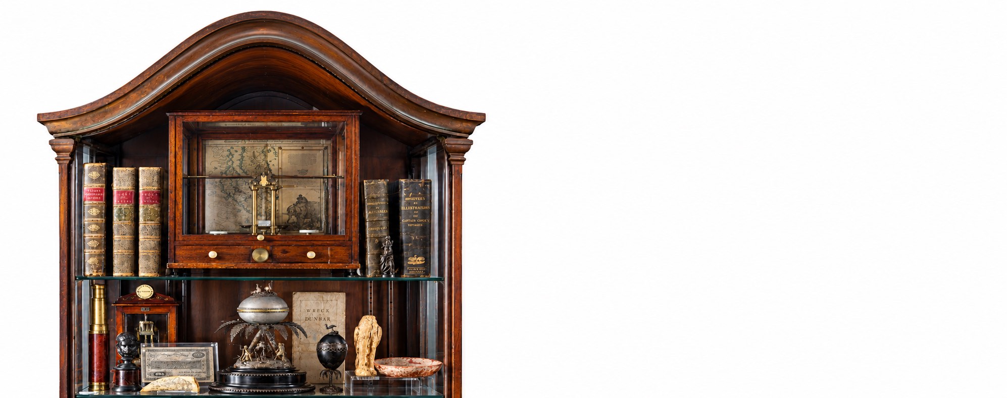 A curved-crest mahogany display cabinet of antique books, instruments and colonial relics